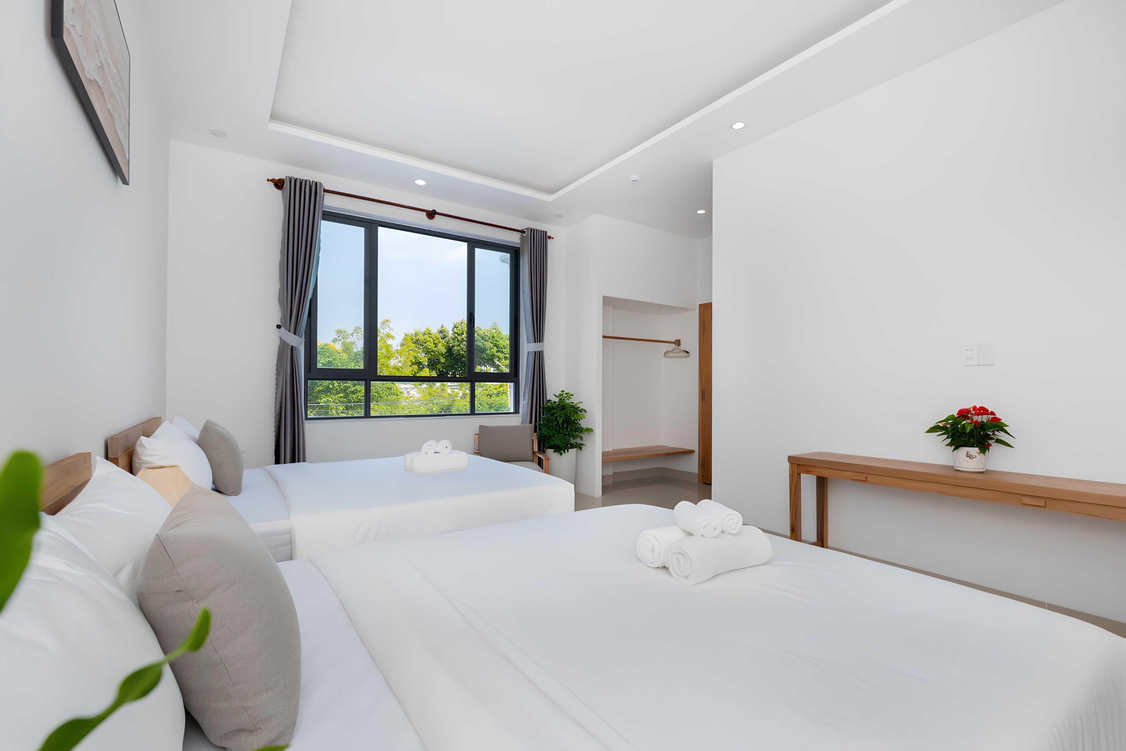 Una habitación de hotel moderna con dos camas, un ventanal grande y una mesita de noche de madera.