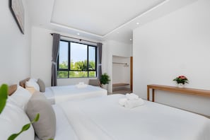 Habitació d'hotel moderna amb dos llits, un gran finestral i una taula de nit de fusta.