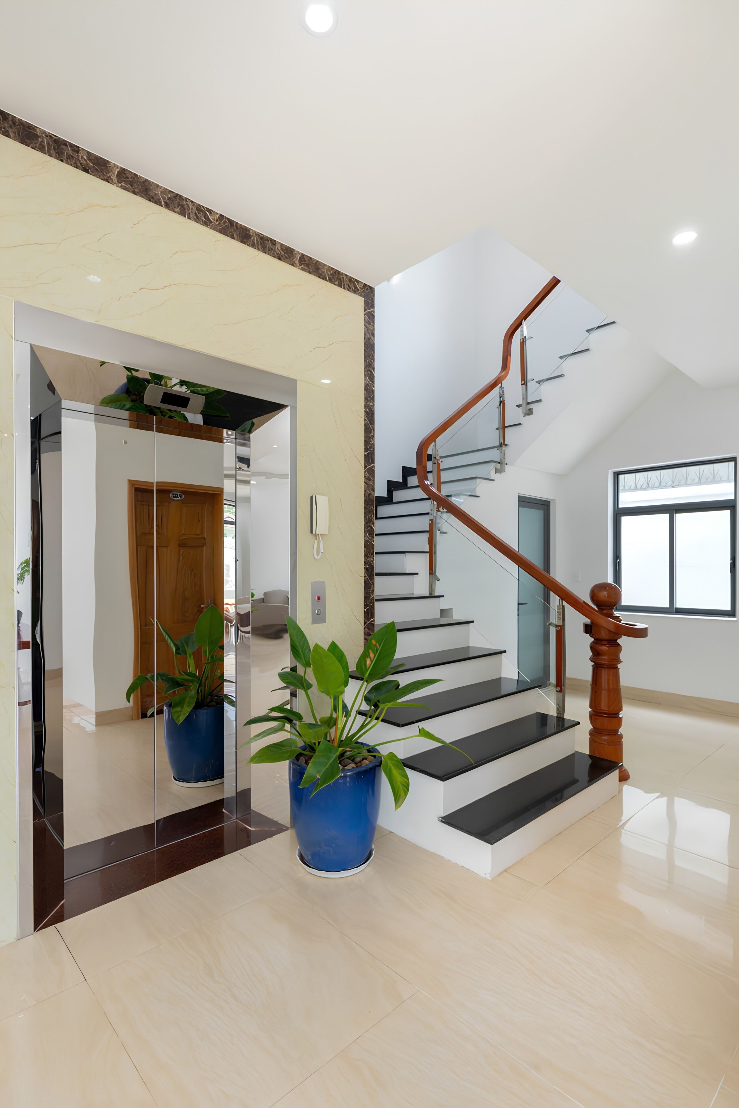A modern interior with a staircase, potted plants, and a clean, reflective floor.