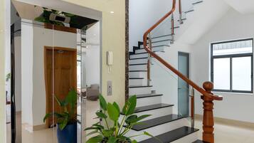 A modern interior with a staircase, potted plants, and a clean, reflective floor.