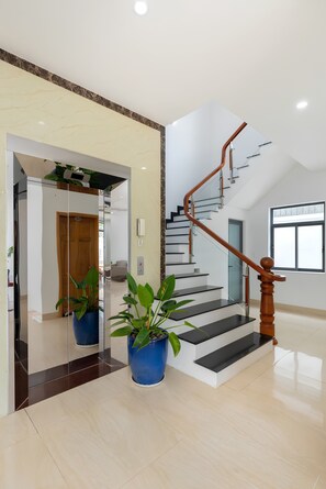Un interior moderno con una escalera, plantas en macetas y un piso limpio y reflectante.