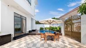A patio with a checkered floor, a pool, and a table with chairs. - Luxury An Home Beach Villa (Rach Dua)