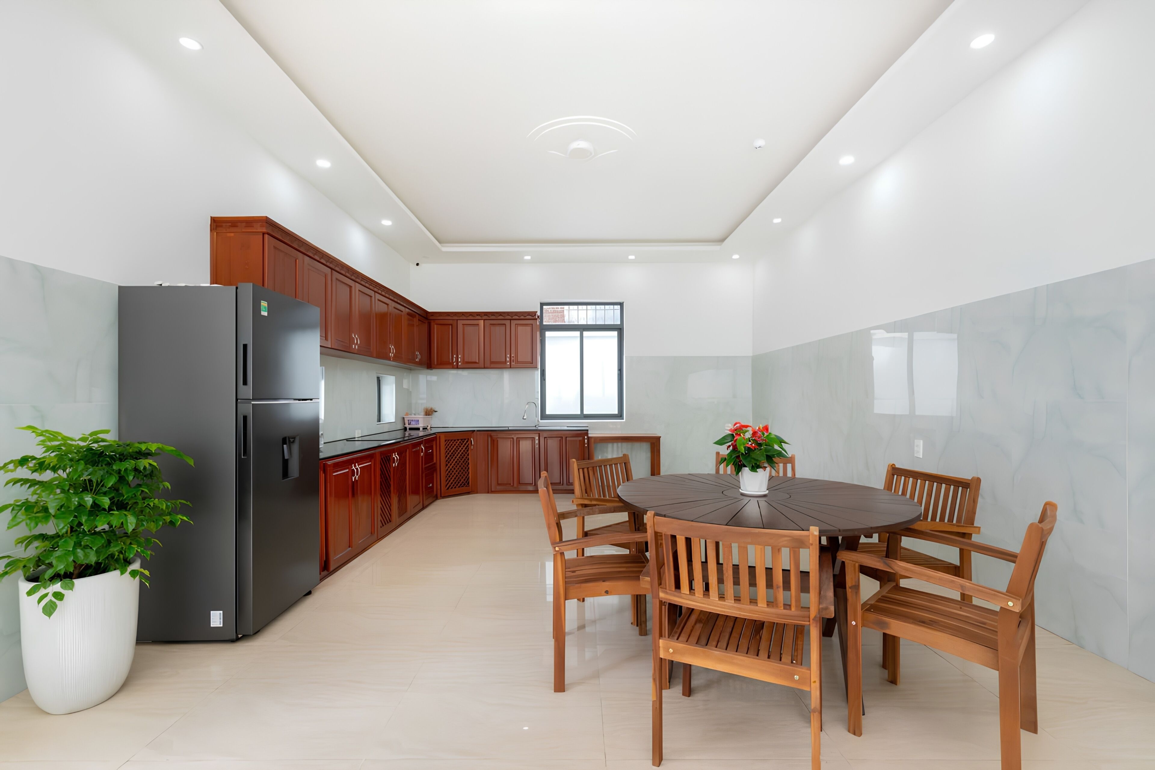 A modern kitchen with wooden cabinets, a black refrigerator, and a dining area with a round table and wooden chairs.