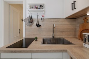 Une cuisine moderne dotée d’un évier en acier inoxydable, d’un plan de travail en bois et d’un porte-ustensiles fixé au mur.