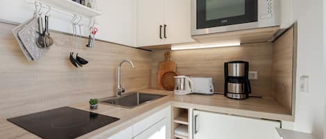 Una cocina moderna con microondas integrado, cafetera y tostadora.