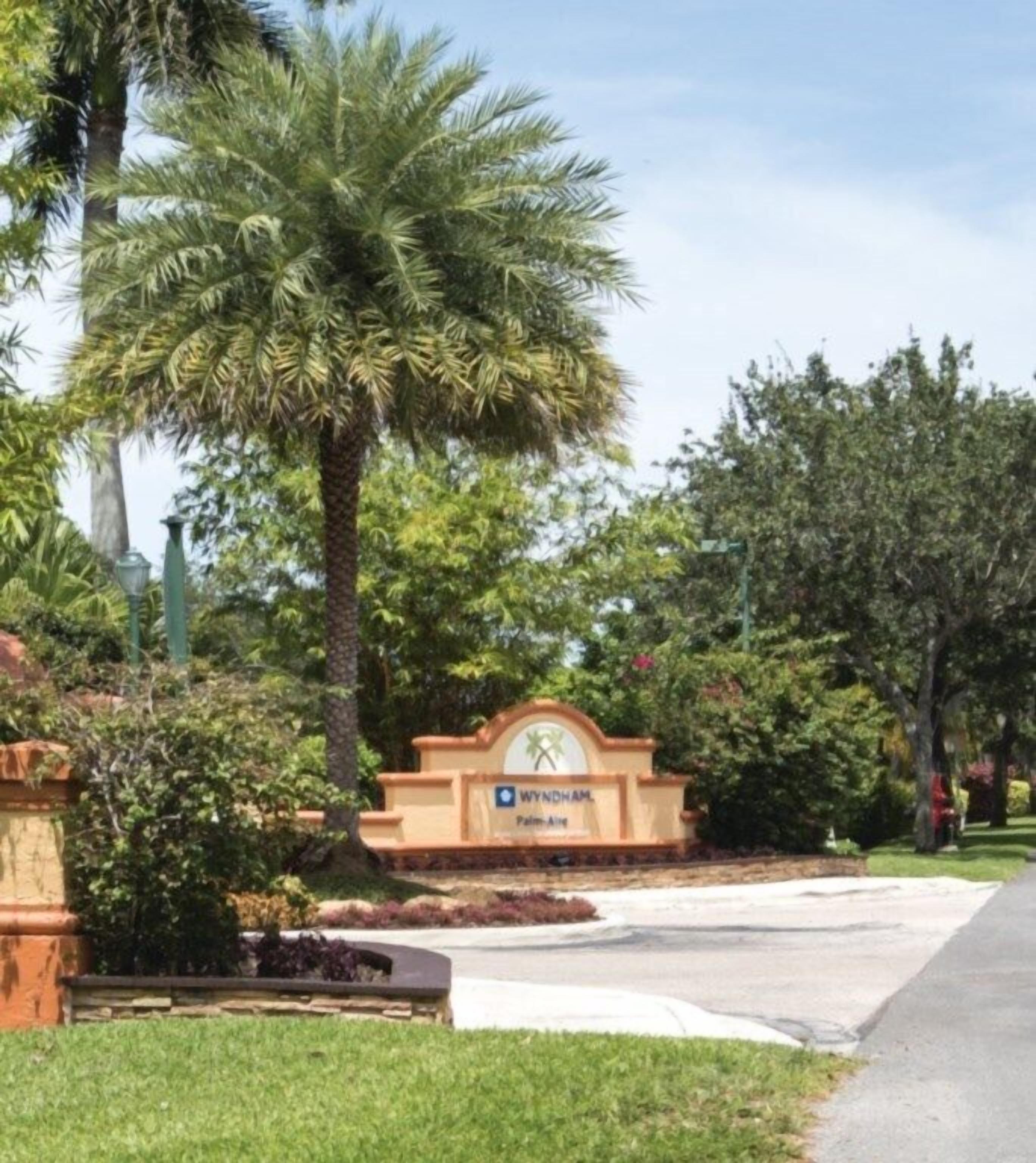 A sign for Wyndham Palm Aire with a palm tree and greenery in the background.