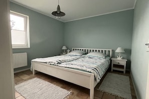Ein Schlafzimmer mit einem Einzelbett, zwei Nachttischen, einem Fenster und einer Heizung.