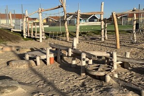 Ein Spielplatz mit Holzkonstruktionen und einem umzäunten Bereich.