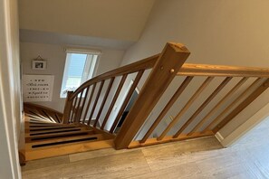 Eine Holztreppe mit Handlauf, die zu einer oberen Etage führt.