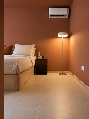 Ein Schlafzimmer mit Bett, Nachttisch, Lampe und Klimaanlage.