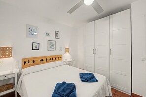 Une chambre à coucher comprenant un lit, une table de chevet, une commode, une armoire et des lampes fixées au mur.