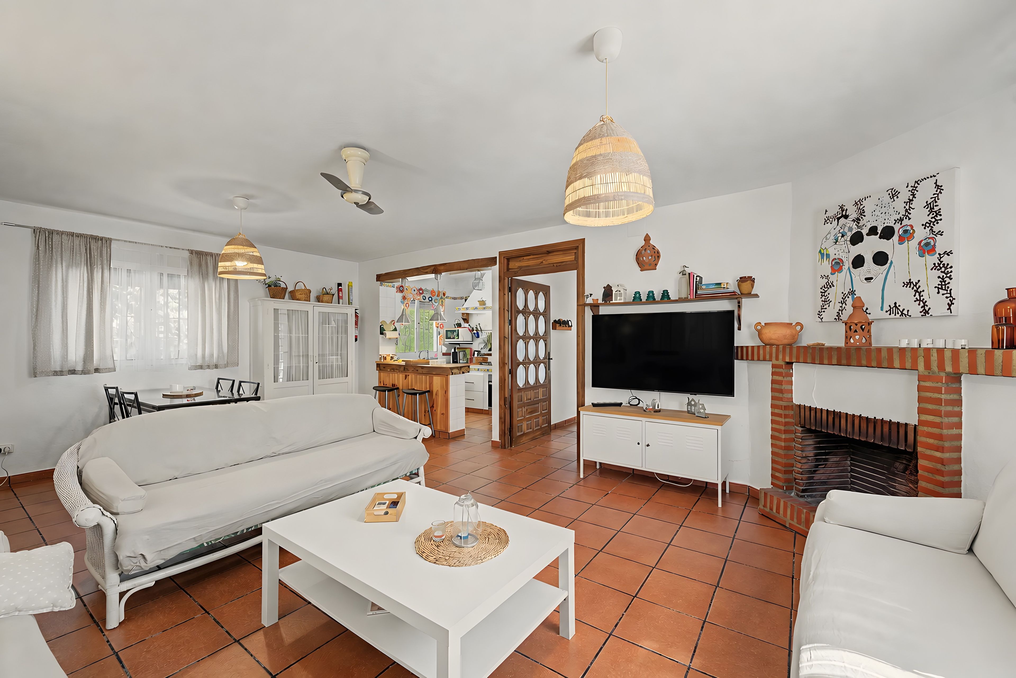 Een woonkamer met een bank, een salontafel, een televisie en een open haard.