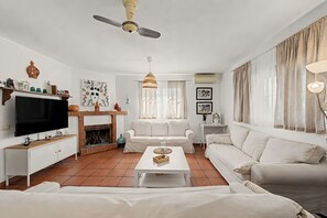 Una sala de estar con televisor, sofá, mesa de centro, chimenea y objetos decorativos.
