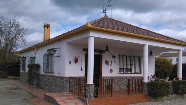 A two-story house with a tiled roof, a covered porch, and a stone foundation.