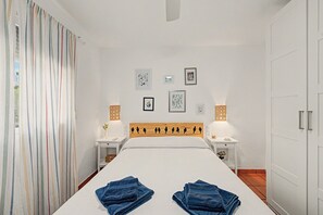 A hotel room with a bed, two bedside tables, a headboard with a bird silhouette, and wall-mounted artwork.