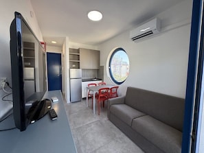 Een ruimtelijk ingerichte leefruimte met kitchenette, eethoek en zithoek.