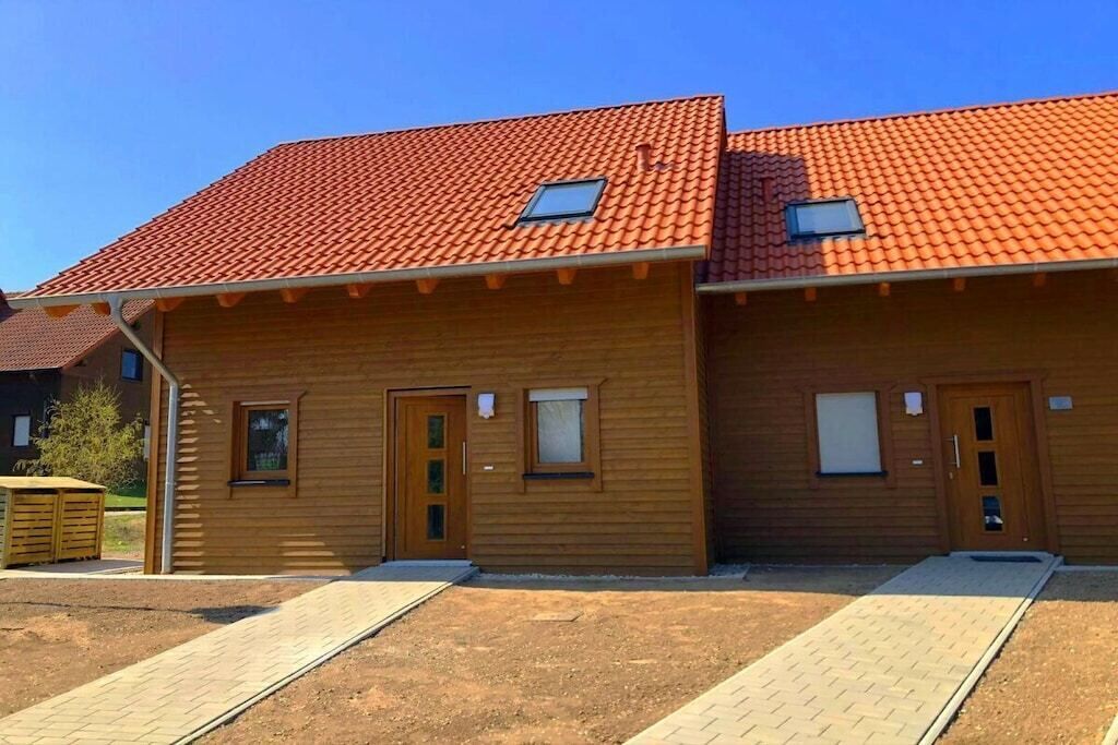 Un edificio de madera con techo de tejas rojas, dos puertas y ventanas.