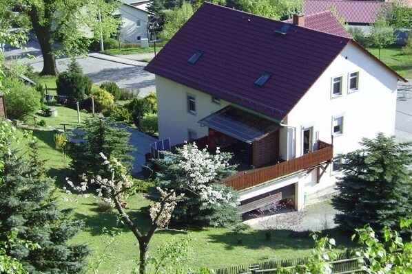 A two-story house with a red roof, a balcony, and a garage. - Holiday apartment with 1 bedroom (Königstein\/ OT Leupoldishain)