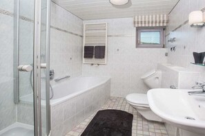 Une salle de bain avec une douche à parois de verre, une baignoire blanche, des toilettes blanches et un lavabo blanc.