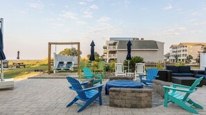 Eine Terrassenfläche mit Sitzgelegenheit im Freien, darunter Stühle und ein Tisch, und Blick auf Gebäude im Hintergrund.