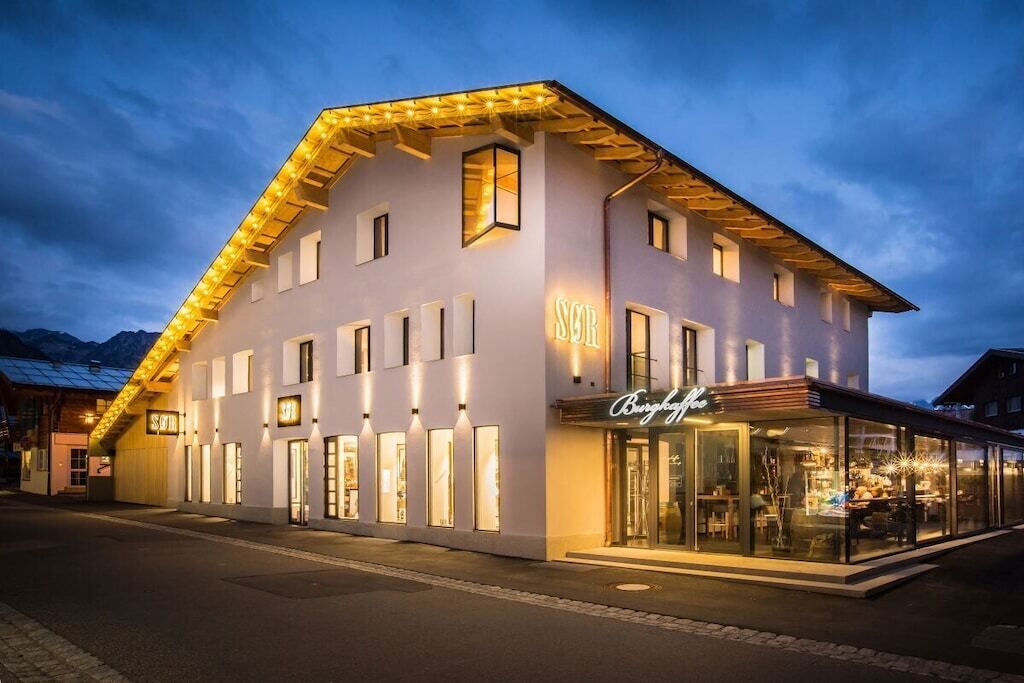 A modern hotel with a prominent 'SOB' sign, large windows, and a well-lit facade.