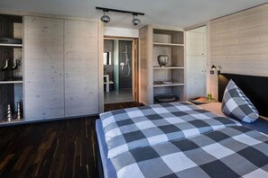 A bedroom with a bed, a wardrobe, a shelf with decorative items, and a shower area. - Holiday apartment with 1 bedroom (Oberstdorf)