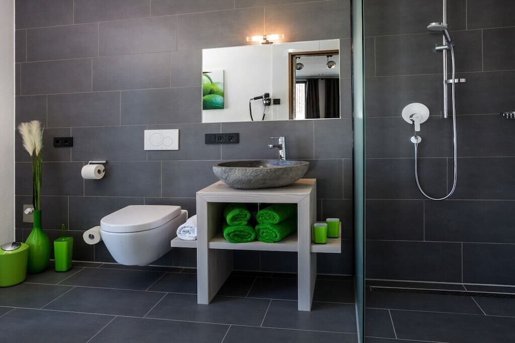Ein modernes Badezimmer mit einem Steintonne, Toilette, Dusche und Spiegel.