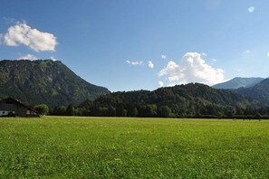 A grassy field with a building and mountains in the background. - Landhof mountain mint (Oberstdorf)