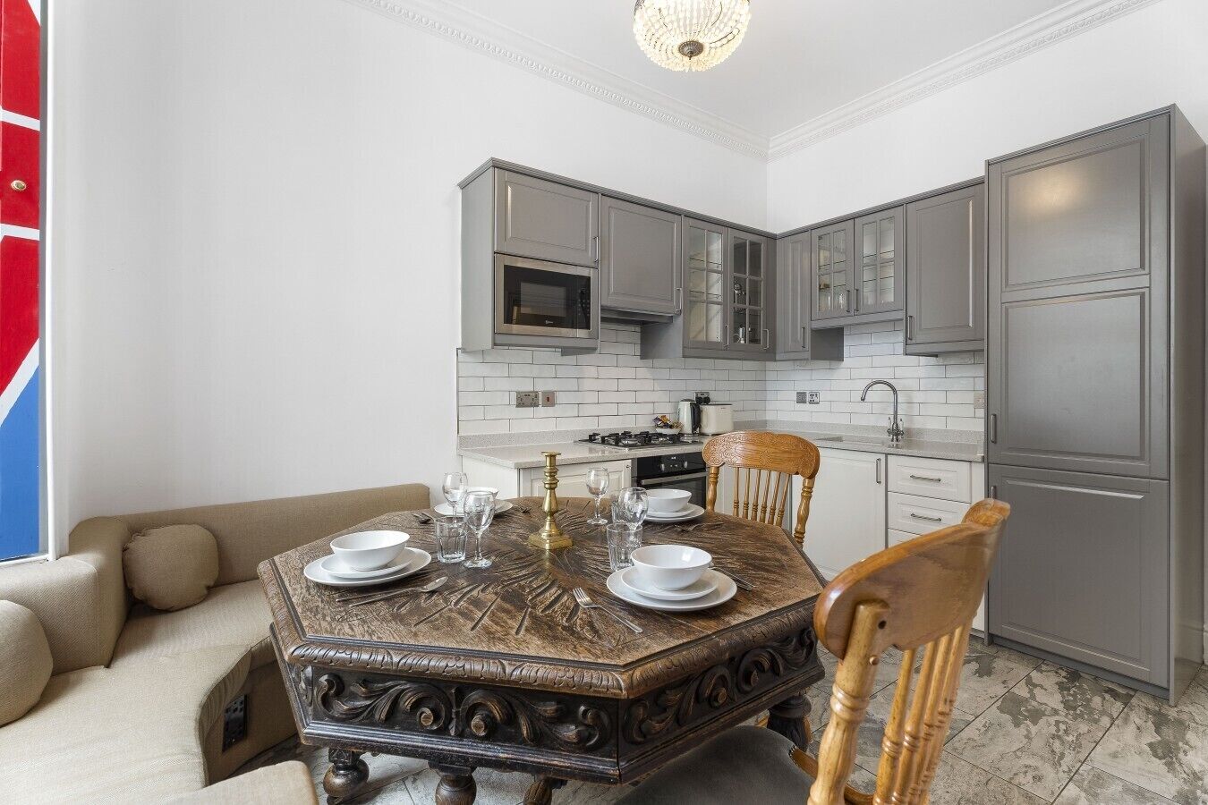 A modern kitchen with grey cabinets, a built-in microwave, and a stainless steel refrigerator.