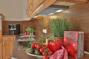 A kitchen counter with a plate of vegetables, a potted plant, and a cookbook titled 'Salate'. - Lavender - Sotterhof (Inzell)