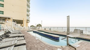 Ein Poolbereich mit Liegestühlen, einem Pool und Blick auf den Strand.