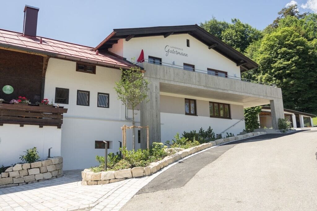 A hotel with a white facade, a red roof, and a balcony with a red umbrella.