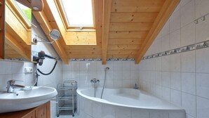 A bathroom with a skylight, a bathtub, and a sink. - Holiday apartment with 1 bedroom (Seebruck)