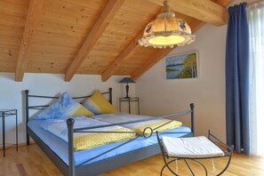 Una camera da letto con soffitto in legno, un letto con struttura in metallo, una lampada da comodino e vista sull'esterno.