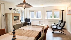 Ein Essbereich mit einem Holztisch, Stühlen, einer Hängeleuchte und Blick ins Freie durch Fenster.