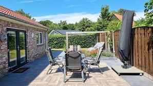 Eine Terrasse mit Tisch und Stühlen, einem überdachten Bereich und einem Holzzaun.