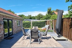 A patio with a table and chairs, a covered area, and a wooden fence. - Holiday apartment OK16 Oostkapelle (Oostkapelle)