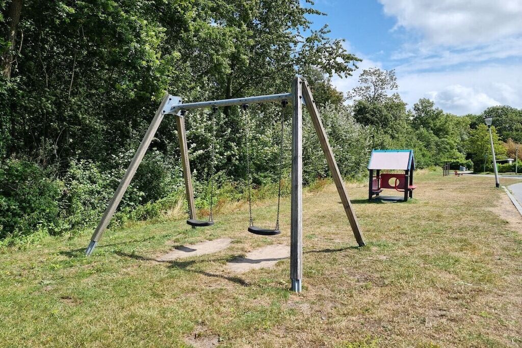 A playground with a swing set and a small shelter.