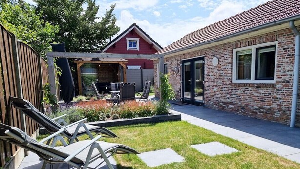 Ein Wohnhaus mit Terrasse, Sitzgelegenheiten im Freien und einer Ziegelhausfassade.
