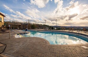 A swimming pool with a stone deck, lounge chairs, and a view of mountains. - Sevierville | Pool & Mountains | 2BR Condo (Sevierville)