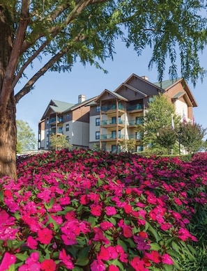 A multi-story hotel with balconies and a landscaped garden with pink flowers. - Sevierville | Pool & Mountains | 2BR Condo (Sevierville)