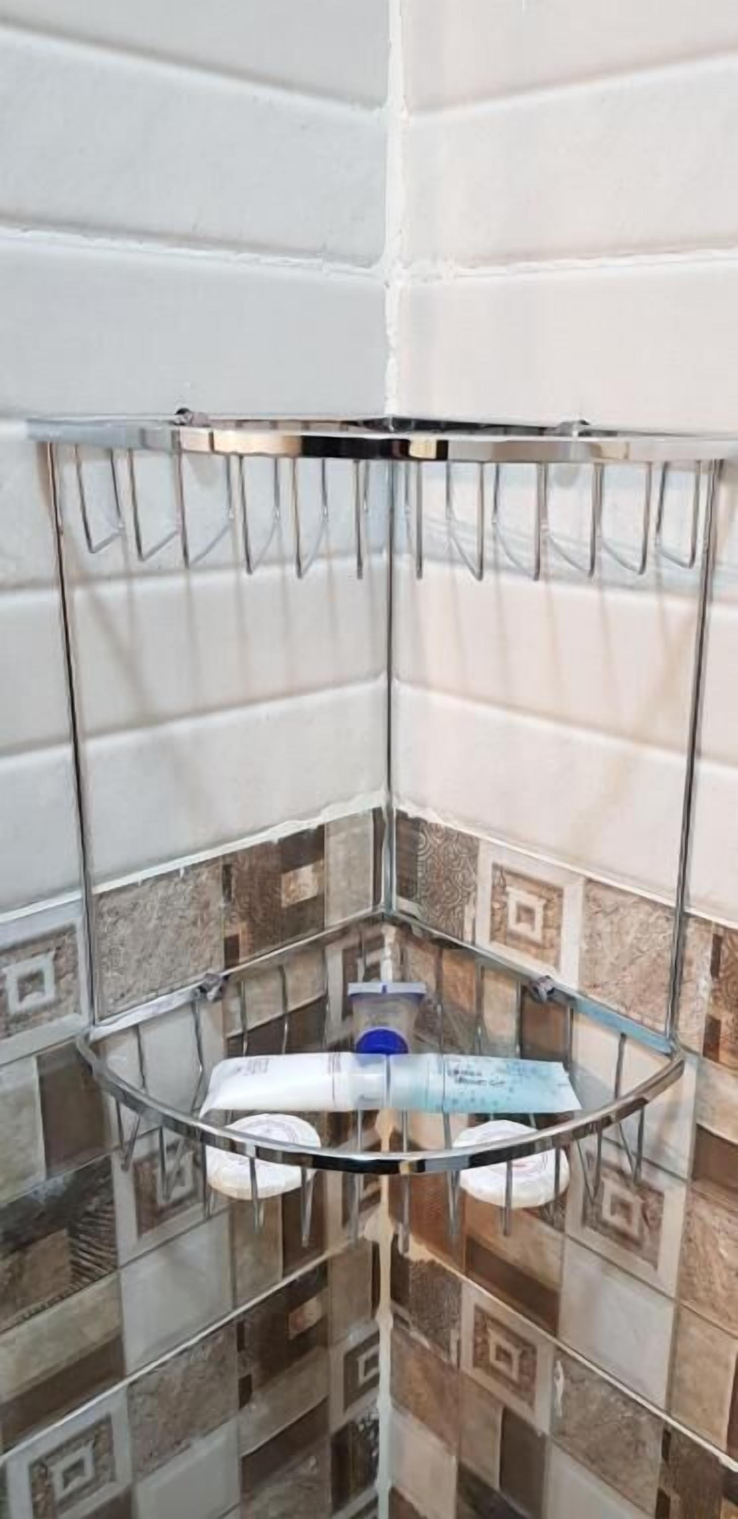 A corner bathroom with a glass shelf holding toiletries.