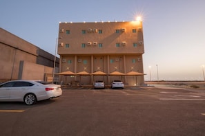 Un immeuble à plusieurs étages avec un espace de stationnement à l’avant.