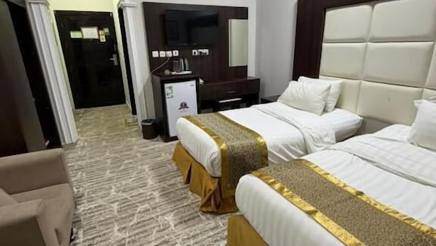 Habitación de hotel con dos camas, televisión, escritorio y candelabro.