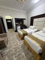 Habitación de hotel con dos camas, televisión, escritorio y candelabro.