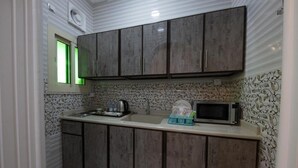 Una cocina con armarios de madera, un fregadero, un microondas y una ventana iluminada con luz verde.