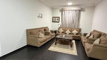 A living room with a dark wood floor, beige sofas, a coffee table, and a chandelier.