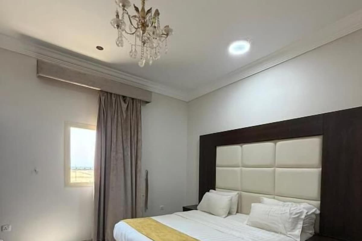 Une chambre d’hôtel avec un grand lit, un lustre et une vue sur l’extérieur.