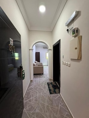 A hallway with a patterned floor, a door with a number sign, and a wall-mounted electrical box. - Jasmine Beach Hotel Suites (Yanbu)