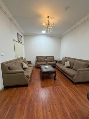 A living room with two sofas, a coffee table, and a chandelier. - Jasmine Beach Hotel Suites (Yanbu)